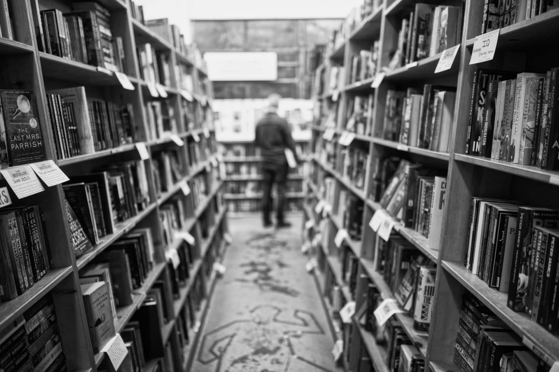 A black and white shot of an aisle of books inside Powells City of Books in Portland, Oregon.
